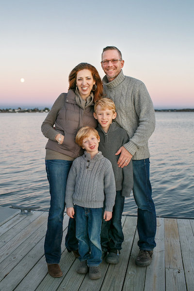 Maria-Jose Tennison with her husband and two sons standing on a dock at sunset.
