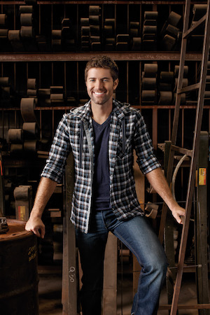Josh Turner smiles and poses in a warehouse.