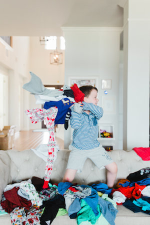 Emily Ley's son throwing clothes while standing on their couch.