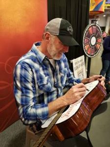 Darryl Worley signing the Jesus Calling guitar at CMA Fest 2019