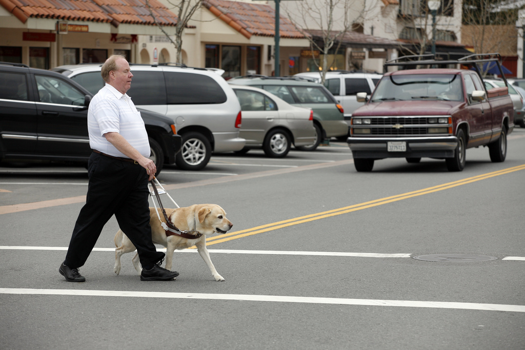 Jesus Calling podcast 419 featuring Michael Hingson & Eve Selis - Hingson shown here walking through a crosswalk with his guide dog